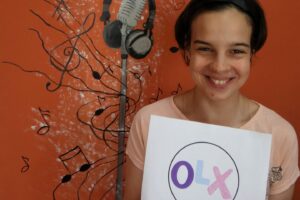 uśmiechnięta dziewczyna trzyma w ręku kartkę z logo OLX